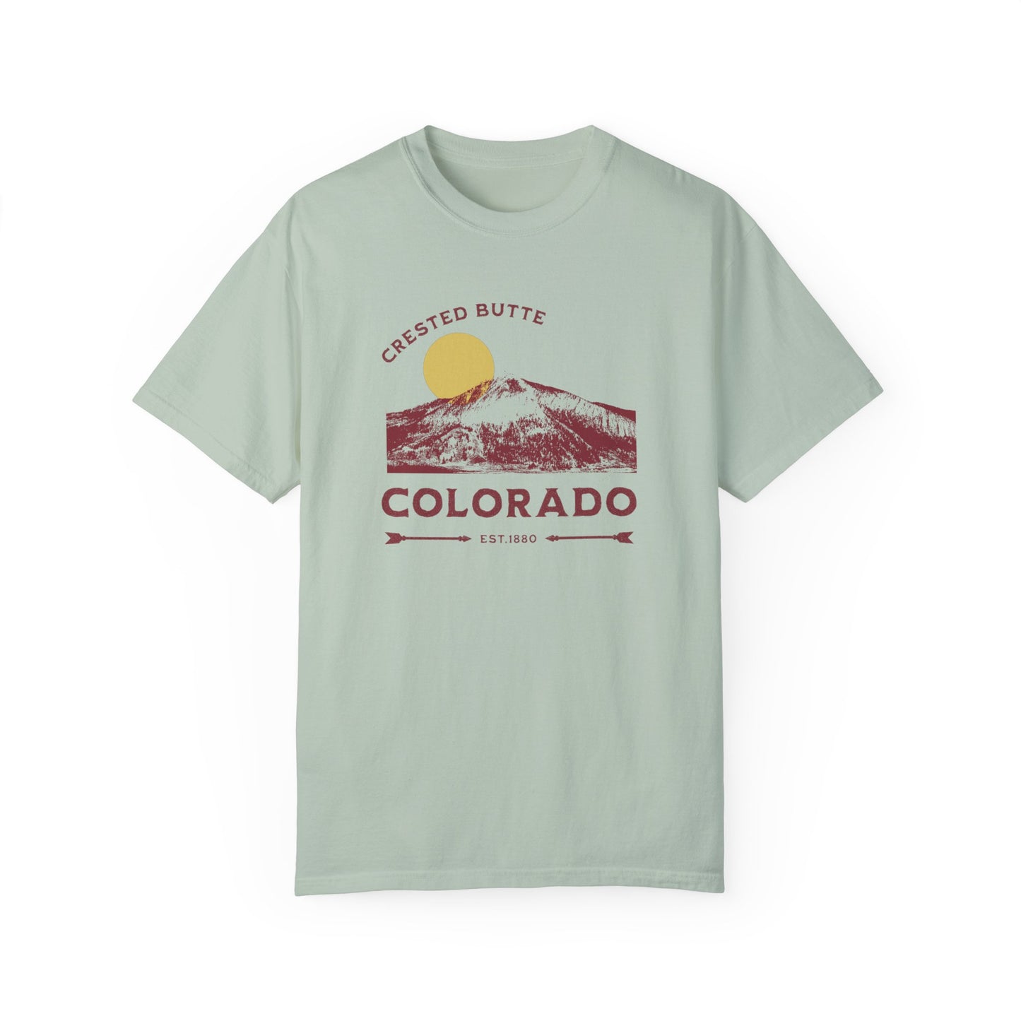 A bay green colored t-shirt with a graphic print of a mountain range and the text 'Crested Butte Colorado'. The design includes a stylized sun motif.