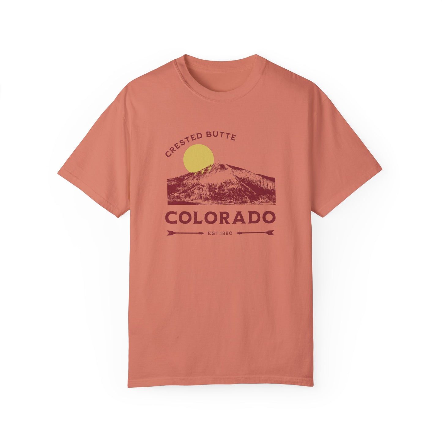 An orange colored t-shirt with a graphic print of a mountain range and the text 'Crested Butte Colorado'. The design includes a stylized sun motif.