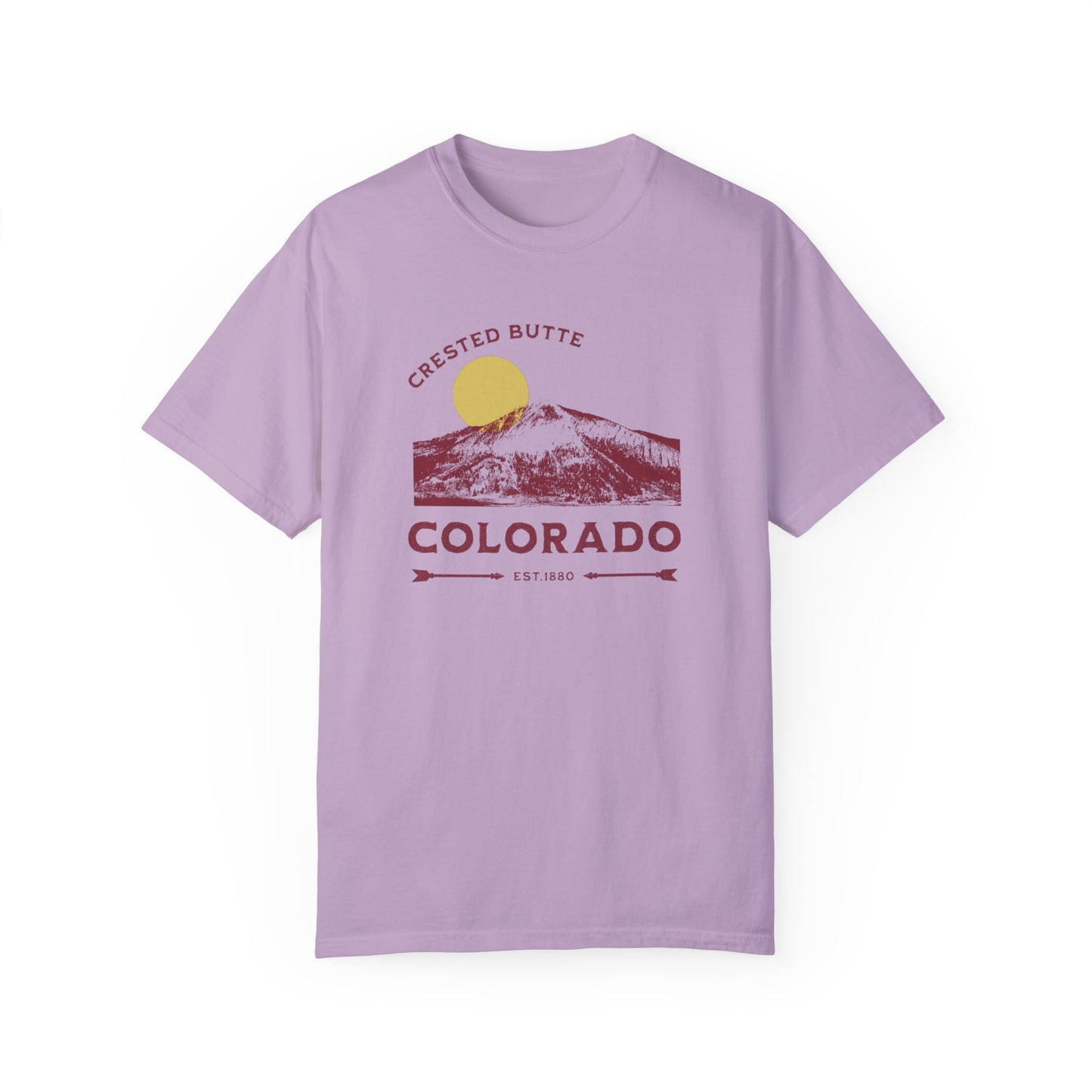 A purple colored t-shirt with a graphic print of a mountain range and the text 'Crested Butte Colorado'. The design includes a stylized sun motif.