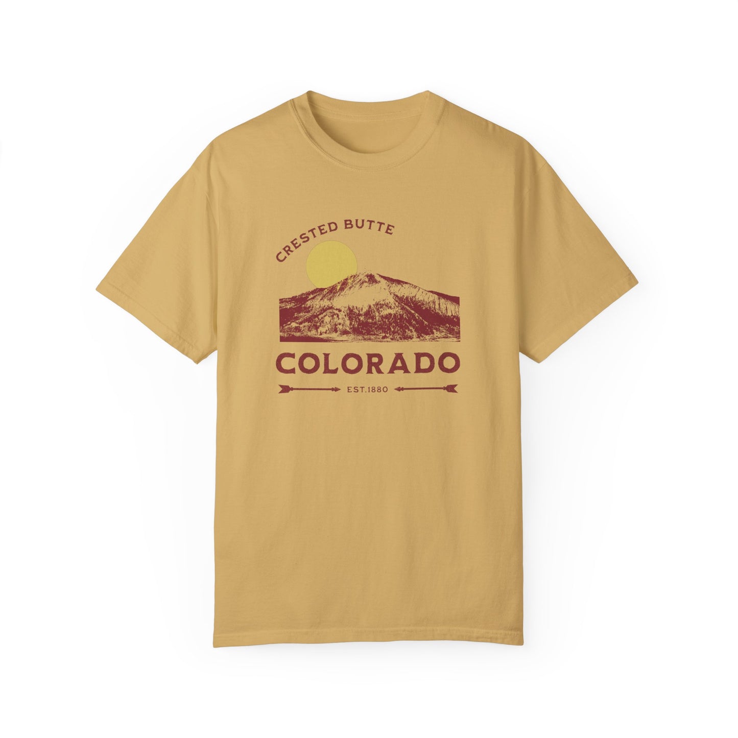 A mustard yellow colored t-shirt with a graphic print of a mountain range and the text 'Crested Butte Colorado'. The design includes a stylized sun motif.