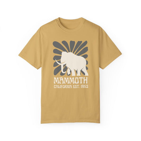 A mustard yellow t-shirt featuring a silhouette of a mammoth with the text 'MAMMOTH CALIFORNIA EST. 1953' on the front.